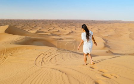 Téléchargez les photos : Jeune femme asiatique marchant dans le désert, Dunes de sable de Dubaï Émirats arabes unis - en image libre de droit