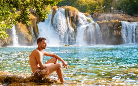 Photo for KRKA waterfalls Croatia during summer, young men sunbathe at the waterfalls of krka national park Croatia on a bright summer evening in the park. - Royalty Free Image