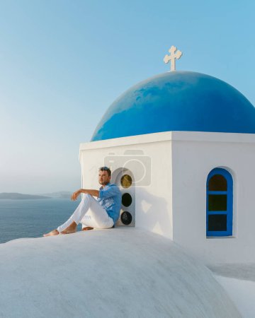 Téléchargez les photos : Young men at Oia Santorini Greece on a sunny day during summer with whitewashed homes and churches, Greek Island Aegean Cyclades - en image libre de droit