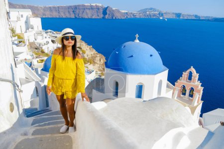 Photo for Asian women visit Oia Santorini Greece on a sunny day during summer with whitewashed homes and churches, Greek Island Aegean Cyclades - Royalty Free Image