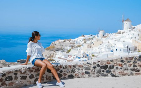 Foto de Asian woman visit Oia Santorini Greece on a sunny day during summer with whitewashed homes and churches, Greek Island Aegean Cyclades - Imagen libre de derechos