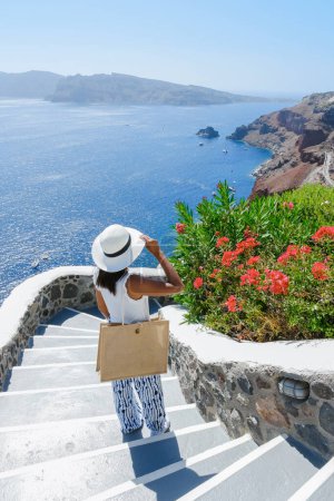 Photo for Asian woman visit Oia Santorini Greece on a sunny day during summer with whitewashed homes and churches, Greek Island Aegean Cyclades - Royalty Free Image