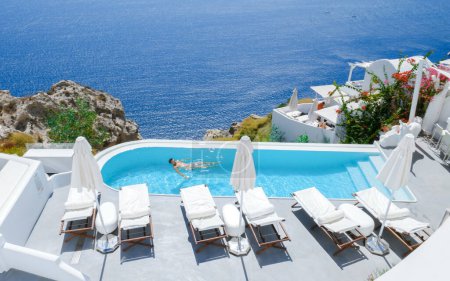Photo for Men relaxing in an infinity swimming pool during vacation at Santorini, swimming pool looking out over the Caldera ocean of Santorini, Oia Greece, Greek Island Aegean Cyclades luxury vacation. - Royalty Free Image