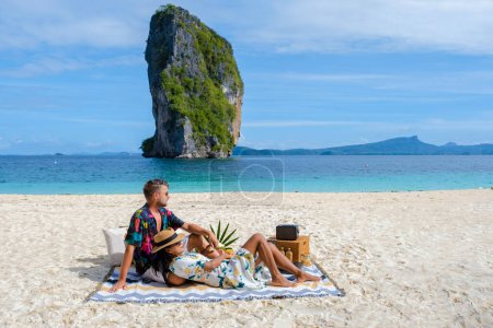 Téléchargez les photos : Koh Poda Beach Krabi Thailand, the tropical beach of Koh Poda Krabi, a couple of men and women on the beach picnic with fruit and drinks - en image libre de droit