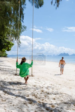 Foto de A couple on a swing on the beach in Phuket Thailand, men and women on a tropical beach in Thailand. - Imagen libre de derechos