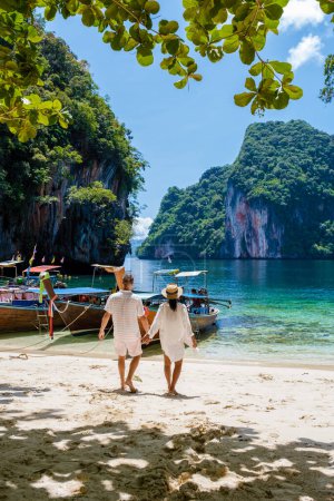 Téléchargez les photos : Men and women at the Tropical lagoon of Koh Loa Lading Krabi Thailand part of the Koh Hong Islands in Thailand. beautiful beach with limestone cliffs and longtail boats - en image libre de droit