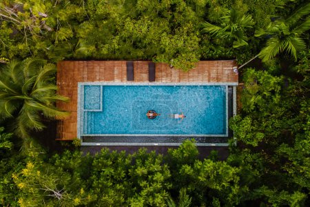 Photo for Drone view of a swimming pool in the jungle, aerial view from a drone above a swimming pool in the rainforest, men and women in a pool - Royalty Free Image