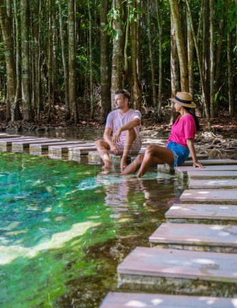 Foto de Couple of men and women visit the Emerald pool and Blue pool in Krabi Thailand, tropical lagoon in a national park with trees, and mangroves with crystal clear water - Imagen libre de derechos