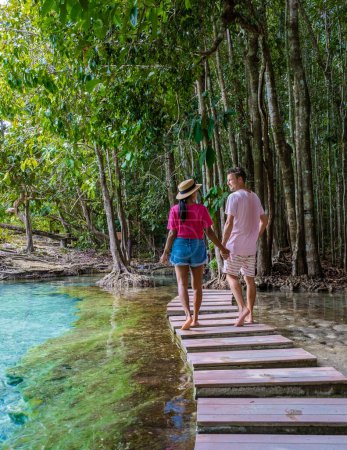 Téléchargez les photos : Couple d'hommes et de femmes visitent la piscine Emeraude et Blue pool à Krabi Thaïlande, lagune tropicale dans un parc national avec des arbres, et des mangroves avec de l'eau cristalline - en image libre de droit