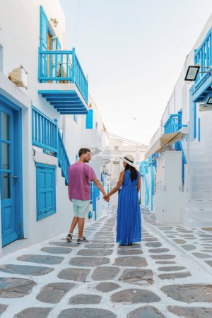 Foto de Pareja romántica de hombres y mujeres en la calle del pueblo griego de Mykonos en Grecia, calles coloridas de Mikonos village.in la mañana - Imagen libre de derechos