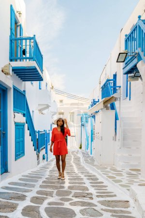 Photo for Young women on the street of Mykonos Greek village in Greece, colorful streets of Mikonos village. Asian woman visits Mykonos village - Royalty Free Image