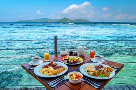 Foto de Breakfast on the beach by the pool with a look over the ocean of La Digue Seychelles,tropical Island - Imagen libre de derechos