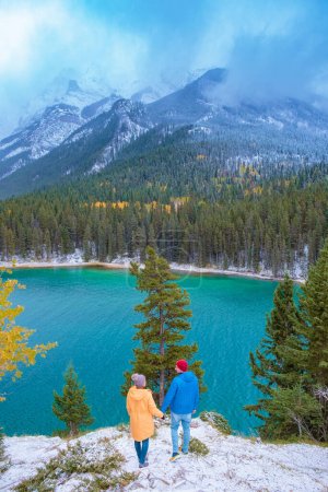 Foto de Minnewanka lake Canadian Rockies in Banff Alberta Canada with turquoise water is surrounded by coniferous forests. Lake Two Jack in the Rocky Mountains of Canada. couple hiking by lake Banff Canada - Imagen libre de derechos