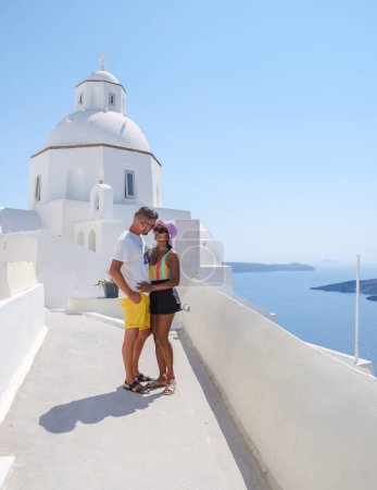 Téléchargez les photos : Couple embrassant et embrassant pendant des vacances romantiques à Santorin en Grèce, les hommes et les femmes visitent le village grec blanchi à la chaux d'Oia . - en image libre de droit