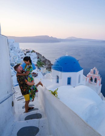 Téléchargez les photos : Couple hugging and kissing on a romantic vacation in Santorini Greece, men and women visit the whitewashed Greek village of Oia . - en image libre de droit
