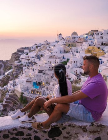 Téléchargez les photos : Couple watching the sunset on vacation in Santorini Greece, men and women visit the Greek village of Oia Santorini. - en image libre de droit