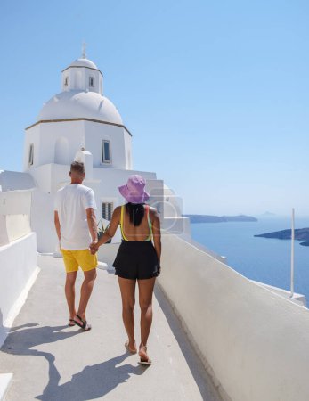 Photo for A couple visit Fira capital of Santorini island and the view of a volcanic caldera, Santorini, Greece.men and women with a white church in Greece - Royalty Free Image