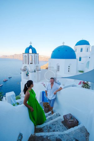 Photo for Couple on vacation in Santorini Greece, and men and women at the Greek village of Oia with a view over the ocean during summer vacation - Royalty Free Image