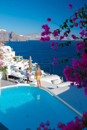 Foto de Couple on vacation in Greece, men and women relaxing by a swimming pool of a luxury resort during summer vacation - Imagen libre de derechos