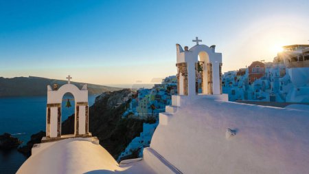 Foto de Sunset by the ocean of Oia Santorini Greece, a traditional Greek village in Santorini with whitewashed churches and blue domes - Imagen libre de derechos