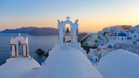 Foto de Sunset by the ocean of Oia Santorini Greece, a traditional Greek village in Santorini with whitewashed churches and blue domes - Imagen libre de derechos