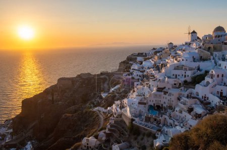 Foto de Puesta de sol con iglesias blancas y cúpulas azules junto al océano de Oia Santorini Grecia. - Imagen libre de derechos