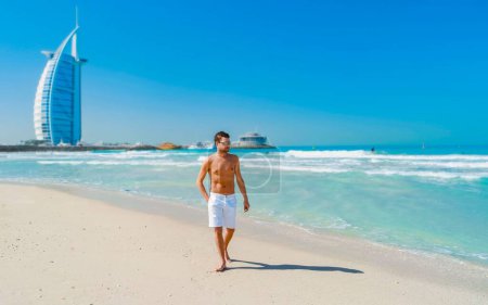 Téléchargez les photos : Jeunes hommes en short de bain sur la plage de Dubaï, Jumeirah beach Dubaï Émirats arabes unis par une journée ensoleillée. - en image libre de droit
