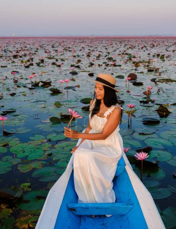Foto de Asian women in a boat at the Beautiful Red Lotus Sea Kumphawapi is full of pink flowers in Udon Thani in northern Thailand. Flora of Southeast Asia. - Imagen libre de derechos
