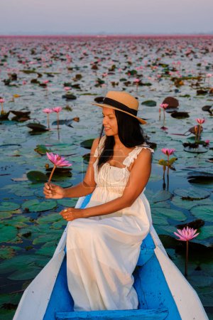 Photo for Thai women in a boat at the Beautiful Red Lotus Sea Kumphawapi is full of pink flowers in Udon Thani in northern Thailand. Flora of Southeast Asia. - Royalty Free Image