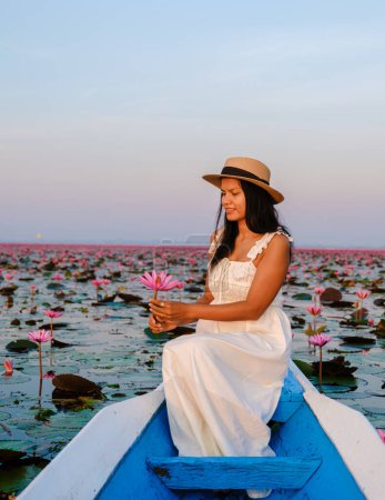 Téléchargez les photos : Femmes asiatiques dans un bateau à la Belle Mer Rouge du Lotus plein de fleurs roses à Udon Thani dans le nord de la Thaïlande. Flore de l'Asie du Sud-Est. - en image libre de droit