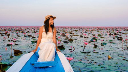 Foto de Thai women in a boat at the Beautiful Red Lotus Sea Kumphawapi is full of pink flowers in Udon Thani in northern Thailand. Flora of Southeast Asia. - Imagen libre de derechos