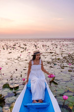 Téléchargez les photos : Asian women in a boat at the Beautiful Red Lotus Sea Kumphawapi is full of pink flowers in Udon Thani in northern Thailand. Flora of Southeast Asia. - en image libre de droit
