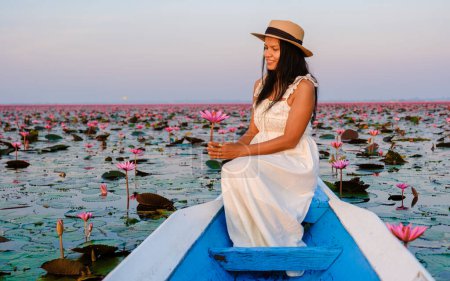 Photo for Asian women in a boat at the Beautiful Red Lotus Sea Kumphawapi is full of pink flowers in Udon Thani in Northern Thailand Isaan. Flora of Southeast Asia. - Royalty Free Image