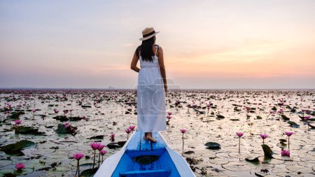 Foto de Mujeres asiáticas en un barco en el hermoso mar de loto rojo Kumphawapi está lleno de flores rosadas en Udon Thani en el norte de Tailandia Isaan. Flora del Sudeste Asiático. - Imagen libre de derechos