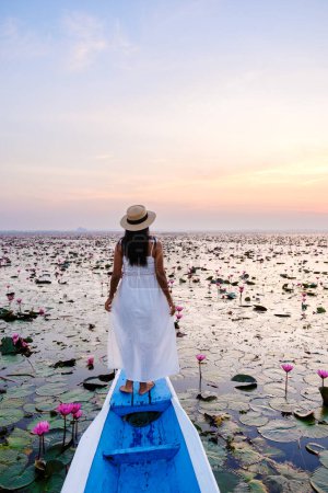 Foto de Asian women in a boat at the Beautiful Red Lotus Sea in Udon Thani in northern Thailand. Flora of Southeast Asia. - Imagen libre de derechos