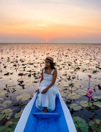 Photo for Asian women in a boat at the Beautiful Red Lotus Sea in Udon Thani in northern Thailand. Flora of Southeast Asia. - Royalty Free Image