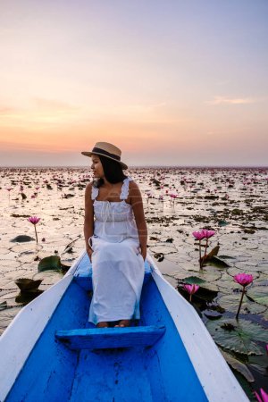Téléchargez les photos : Femmes asiatiques dans un bateau à la Belle Mer Rouge Lotus Kumphawapi est plein de fleurs roses à Udon Thani dans le nord de la Thaïlande Isaan. Flore de l'Asie du Sud-Est. - en image libre de droit