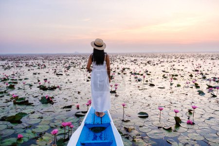 Photo for Asian women in a boat at the Beautiful Red Lotus Sea in Udon Thani in northern Thailand. Flora of Southeast Asia. - Royalty Free Image