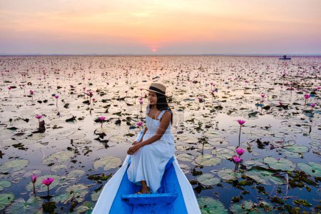 Photo for Thai women in a boat at the Beautiful Red Lotus Sea Kumphawapi is full of pink flowers in Udon Thani in northern Thailand. Flora of Southeast Asia. - Royalty Free Image