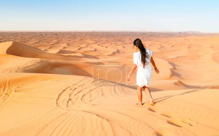 Photo for Young Asian woman walking in the desert, Sand dunes of Dubai United Arab Emirates - Royalty Free Image