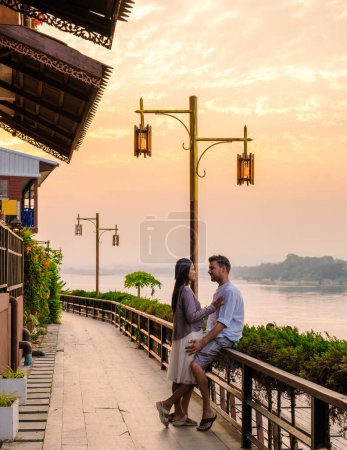 Photo for A couple of men and women visit Chiang Khan village North Eastern Thailand alongside the Mekong river. A traditional village with wooden house at sunset - Royalty Free Image