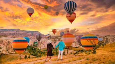Cappadocia Turkey during sunrise, a couple mid age men and women on vacation in the hills of Goreme Cappadocia Turkey, men and woman looking sunrise with hot air balloons in Cappadocia Turkey