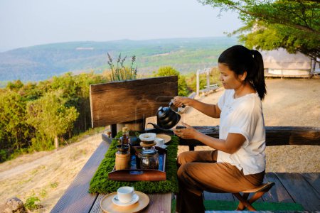 Photo for Women making drip coffee in the mountains of Thailand. Asian woman preparing coffee on a tented camp - Royalty Free Image