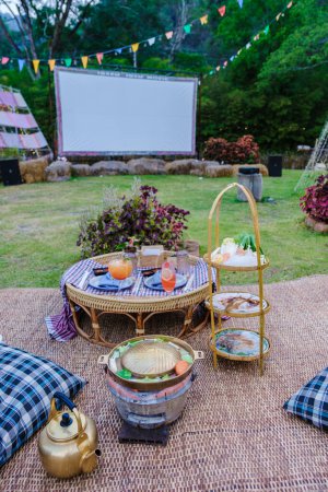 Téléchargez les photos : Film de cinéma en plein air dans un jardin tropical avec lumières de Noël. H - en image libre de droit