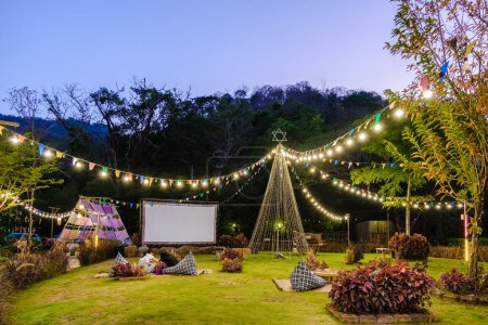 Téléchargez les photos : Film de cinéma en plein air dans un jardin tropical avec lumières de Noël. H - en image libre de droit