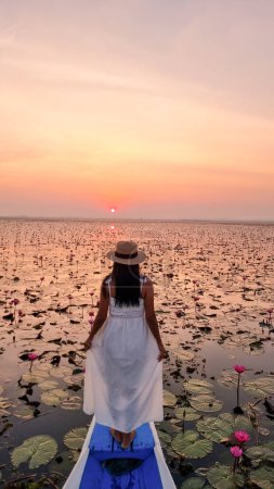 Foto de Asian women in a boat at the Beautiful Red Lotus Sea Kumphawapi is full of pink flowers in Udon Thani in Northern Thailand Isaan. Flora of Southeast Asia. - Imagen libre de derechos
