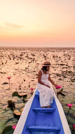 Foto de Asian women in a boat at the Beautiful Red Lotus Sea Kumphawapi is full of pink flowers in Udon Thani in Northern Thailand Isaan. Flora of Southeast Asia. - Imagen libre de derechos