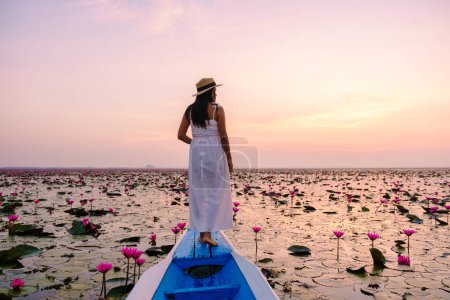 Photo for The sea of red lotus, Lake Nong Harn, Udon Thani, Thailand, Asian woman with a dress and hat in a wooden boat at the red lotus lake. - Royalty Free Image