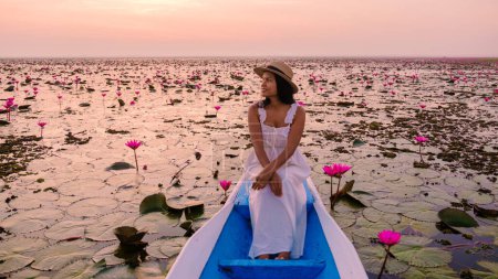 Foto de El mar de loto rojo, Lago Nong Harn, Udon Thani, Tailandia, Mujer asiática con un vestido y sombrero en un barco de madera en el lago de loto rojo. - Imagen libre de derechos