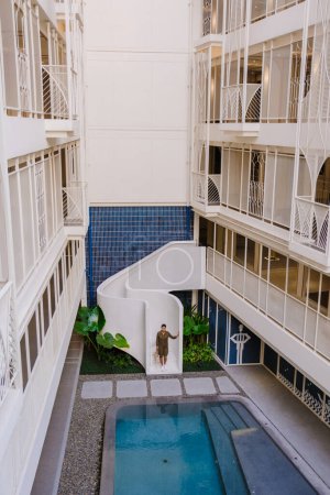 Téléchargez les photos : Femmes asiatiques marchant dans les escaliers au bord d'une piscine dans un hôtel de luxe art déco architecture des années 80 - en image libre de droit